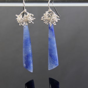 May include: A pair of dangle earrings with blue gemstone drops and silver wire accents.