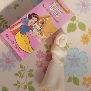 May include: A pink and white box with the words "Snow White" and "Scented Soap Model" on it. The box features a cartoon image of Snow White from the Disney movie. A white plastic figurine of Snow White is also pictured.