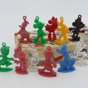 Könnte beinhalten: Ein Set mit zehn Plastik-Anhängern mit den Figuren Mickey Mouse, Donald Duck, Goofy und Pluto. Die Anhänger sind in verschiedenen Farben, darunter Rot, Grün, Blau, Gelb und Schwarz. Die Anhänger sind alle in verschiedenen Posen und haben oben ein Loch zum Aufhängen.