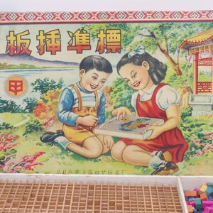 May include: A vintage wooden game box with a colorful illustration of two children playing a game. The box lid features the Chinese text "板拼连连看" and a red logo with a stylized "B". The box is open, revealing a wooden grid and a pile of colorful wooden blocks.