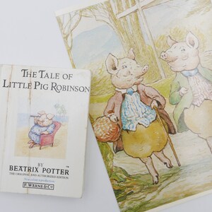 May include: A vintage children's book titled "The Tale of Little Pig Robinson" by Beatrix Potter. The book cover features an illustration of a pig wearing a blue shirt and sitting in a red chair. The book is a classic children's story.