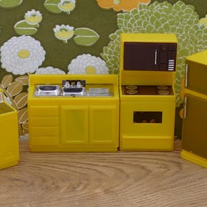 May include: A yellow toy kitchen set with a sink, oven, stovetop, refrigerator, and washing machine. The appliances are all yellow with black accents.
