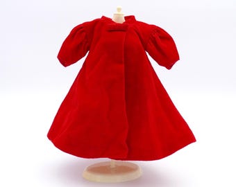 May include: A red velvet doll coat with puffed sleeves and a bow at the neckline.