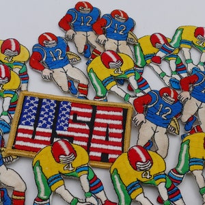 May include: A collection of colourful embroidered patches featuring football players in various poses. The patches are decorated with numbers, including "12" and "4", and the word "USA" is prominently displayed on a red, white and blue patch.