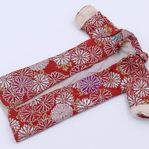 May include: A red and white floral patterned robe with a white lining. The robe has long sleeves and is open at the front.