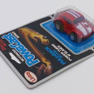 May include: A red, white, and blue toy car with a pull-back motor. The car is in a plastic package with the words "PowerCast Series" and "Lintoy" on it.