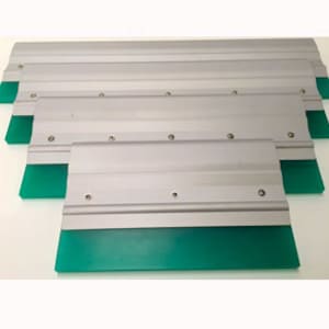 May include: Several silver screen printing squeegees with vibrant green blades. The squeegees are arranged in a slightly overlapping pattern, highlighting their rectangular shape and metal construction. The blades are made of a flexible, durable material.