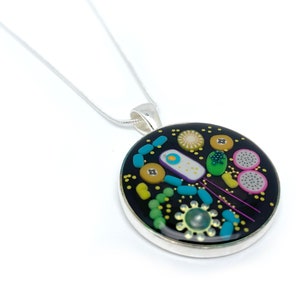 May include: A silver chain necklace with a round pendant featuring a black background with colourful bacteria and viruses. The pendant is made of resin and has a silver rim.