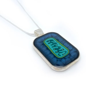 May include: A silver chain necklace with a rectangular pendant featuring a blue and green illustration of a mitochondrion.