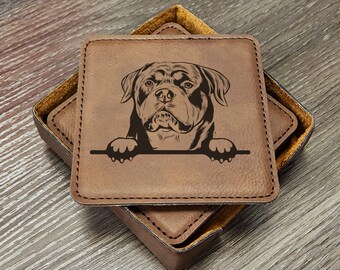 May include: Brown leather coasters with a black and white engraved image of a Rottweiler dog peeking over the top. The coasters are in a square holder.