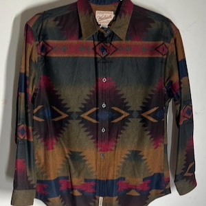 May include: A long-sleeved button-down shirt with a geometric pattern in shades of brown, red, blue, and green. The shirt has a label that reads "Wrangler".