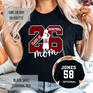 A person wearing a black t-shirt with a basketball graphic and the number 26, along with the text "CLASS OF 26 MOM".