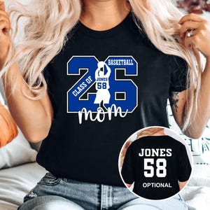 A woman wearing a black t-shirt with a basketball-themed graphic and text printed on it.