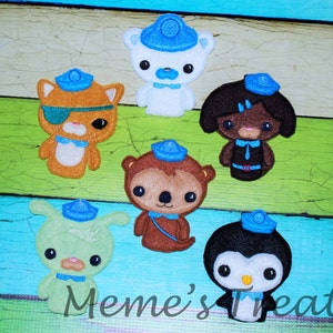 May include: Set of six felt finger puppets featuring characters from the children's television show, 'The Backyardigans'. The puppets are all wearing blue and white sailor hats. The characters include a brown bear, a green alien, a penguin, a cat, a polar bear, and a girl with brown hair.