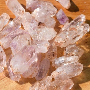 May include: A white ceramic mug with a black handle and the text "But First, Coffee" in a black, handwritten-style font. The mug is on a white surface.