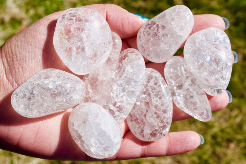 May include: A collection of eight clear quartz crystal tumbled stones with a cloudy, milky appearance. The stones are smooth and polished, with a variety of sizes and shapes.