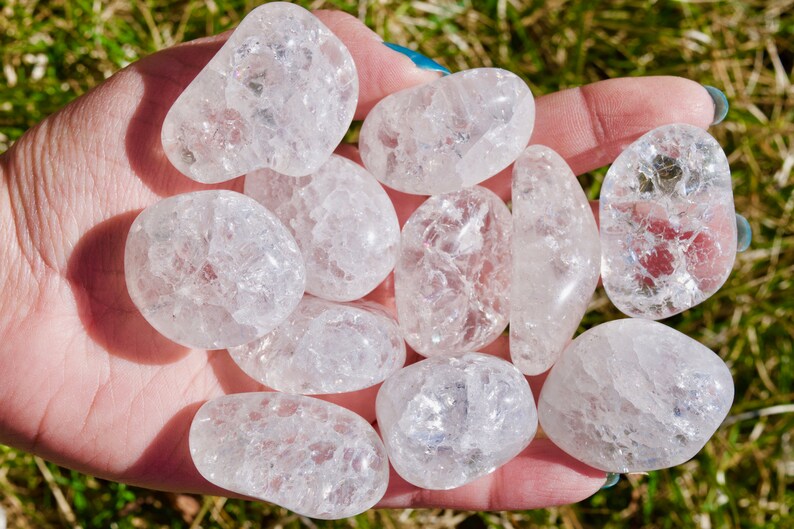 May include: A collection of ten clear quartz tumbled stones with a cloudy, milky appearance. The stones are smooth and polished, with a variety of sizes and shapes.