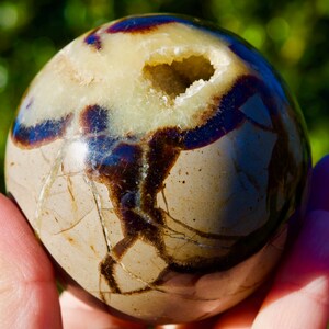 May include: A white ceramic mug with a black handle and the text "But First, Coffee" in a black, bold font. The mug is on a white surface. The mug is likely for hot beverages.