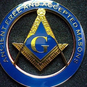 Puede incluir: Un emblema de coche de metal azul y dorado con el texto "Ancient Free and Accepted Masons".