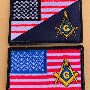 May include: Two embroidered patches featuring the American flag and a Masonic symbol. The top patch has a blue background with the flag in the upper left corner and the Masonic symbol in the lower right corner. The bottom patch has a red, white, and blue American flag with the Masonic symbol in the lower right corner.