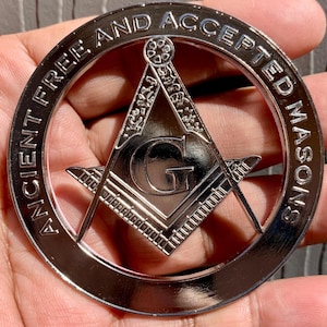 May include: Silver-toned metal car emblem with the words "Ancient Free and Accepted Masons" around the edge. A silver-toned Masonic square and compass with a "G" in the center is inside the circle.