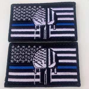 以下が含まれることがあります： 薄い青いラインと、垂れた効果のある白い頭蓋骨が刺繍された、黒と白の2つのパッチ。パッチは黒い背景になっています。