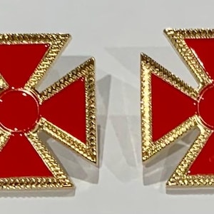 May include: A pair of red and gold cross earrings. The crosses are outlined in gold and have a red enamel finish.