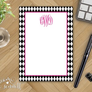 May include: A white notepad with a black and white diamond pattern border. The notepad has a pink monogrammed initial "C.W.D." in the top center.