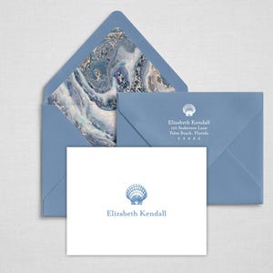 May include: A white stationery card and two dusty blue envelopes. The card features a blue seashell icon and the text Elizabeth Kendall. One envelope has a marbled blue and white liner, while the other shows the name and address Elizabeth Kendall.