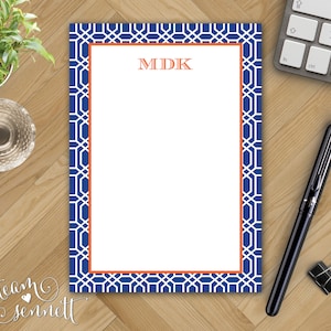 May include: Blue and white patterned notepad with an orange border. The notepad has a white space for writing with the initials "MDK" printed in orange at the top.