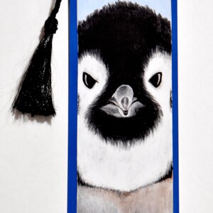 May include: A blue and white penguin bookmark with a black tassel. The penguin is looking directly at the viewer with a serious expression.