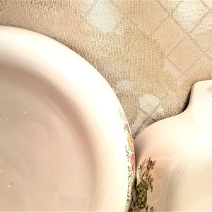 May include: Two white Corning Ware baking dishes with a floral pattern. The larger dish is 9 1/2 inches and is marked "Range, Oven, Microwave, Corning, NY, USA, 378 MA".