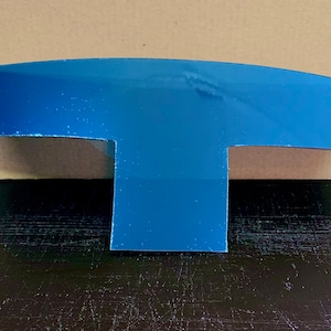 May include: A blue plastic T-shaped sign with a curved top.