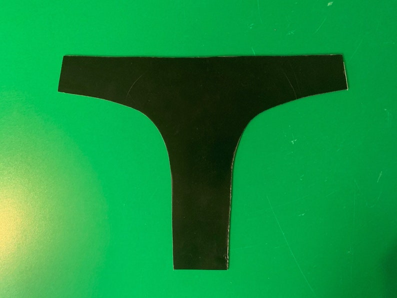 May include: Black underwear cut out of paper. The underwear is shaped like a T with a wide waistband.