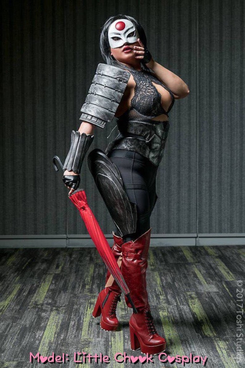Peut inclure: Une femme v&ecirc;tue d'un costume noir et argent avec un parapluie rouge. Elle porte un masque blanc avec un cercle rouge. Le texte "Model: Little Chook Cosplay" est en bas de l'image.