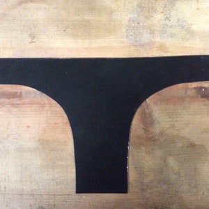 Puede incluir: Un recorte de tela negro en forma de camiseta sobre una superficie de madera.