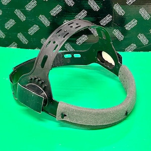 May include: Black adjustable headband with a grey padded band. The headband is made of plastic and has a textured surface.