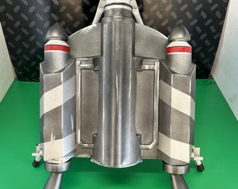 Peut inclure: Un propulseur dorsal de couleur argentée comprenant un corps cylindrique central flanqué de deux propulseurs latéraux. Chaque propulseur latéral est orné de rayures blanches diagonales et d'une bande rouge horizontale près du sommet.