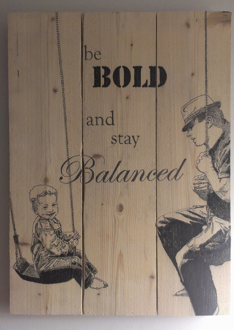 May include: A wooden sign with the text "be BOLD and stay Balanced" printed in black. The sign features a black and white illustration of a child on a swing and a man standing next to the swing.