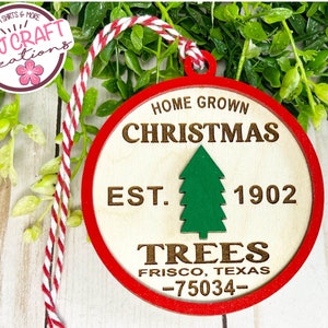 May include: A round wooden Christmas ornament with a red border. The ornament has the text "Home Grown Christmas Est. 1902 Trees Frisco, Texas -75034- ". A green Christmas tree is in the center of the ornament.