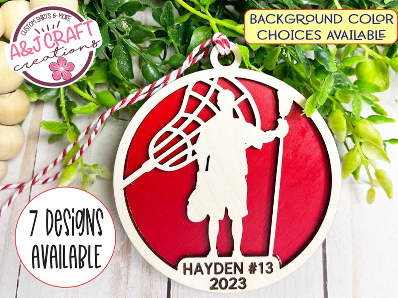 May include: A red and white wooden lacrosse player ornament with the text "HAYDEN #13 2023".