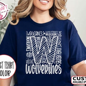 May include: A navy blue t-shirt with a white graphic of the letter "W" made up of the word "Wolverines" repeated multiple times. The text "WOLVERINES" is written below the letter.