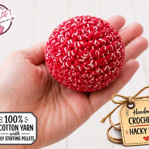 May include: A red and white crocheted hacky sack made with 100% cotton yarn and poly stuffing pellets. The handmade ball is held in a hand. A tag reads "Handmade Crocheted Hacky Sack".