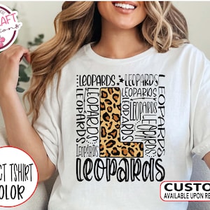 May include: White t-shirt with a large letter L made of a leopard print pattern. The letter L is surrounded by the word "LEOPARDS" repeated multiple times.
