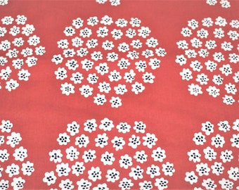 Puede incluir: Tela roja con un patrón floral blanco. Las flores están dispuestas en círculos y tienen centros negros.
