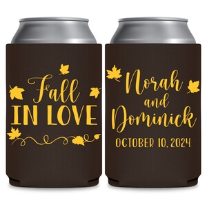 May include: Two brown can coolers with yellow text and leaf designs. The left cooler says 'Fall in Love' with a swirl design and leaves. The right cooler says 'Norah and Dominick' with a date of 'October 10, 2024'.