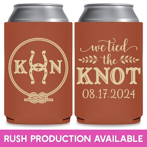 May include: Two brown and beige can coolers with a rustic wedding theme. The cooler on the left has a horseshoe and rope design with the letters 'K' and 'N' on either side of the horseshoe. The cooler on the right has the text 'we tied the knot' with a date of '08.17.2024'.