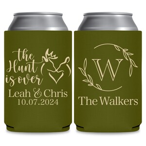 May include: Two green can coolers with white text. The cooler on the left has a deer silhouette and the text 'The Hunt is Over Leah & Chris 10.07.2024'. The cooler on the right has a wreath with the letter 'W' in the center and the text 'The Walkers'.