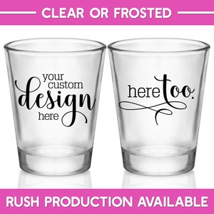 May include: Two clear shot glasses with black text. The first shot glass says 'your custom design here' and the second shot glass says 'here too.' The shot glasses are on a white background.