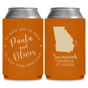 May include: Two orange can coolers with white text. The left cooler says 'To have and to hold Paula and Oliver to keep your beer cold.' The right cooler has a white outline of the state of Georgia with a heart in the middle. The text below the state says 'Savannah Georgia 07.19.2024.'